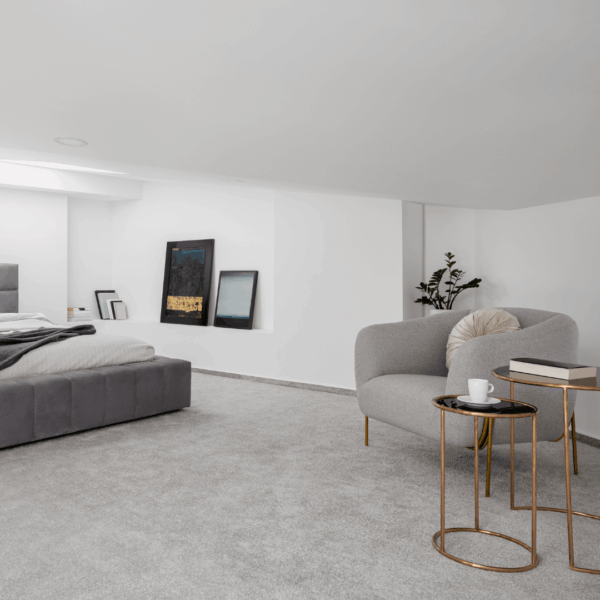 A modern minimalist bedroom featuring a grey bed, cozy armchair, and stylish decor.