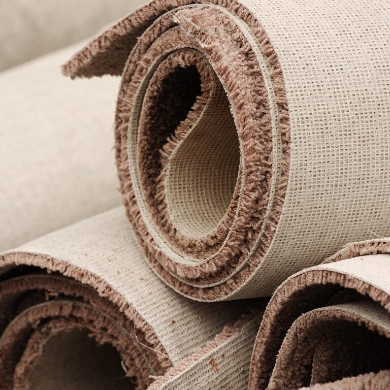 Close-up of rolled beige carpets with brown edges